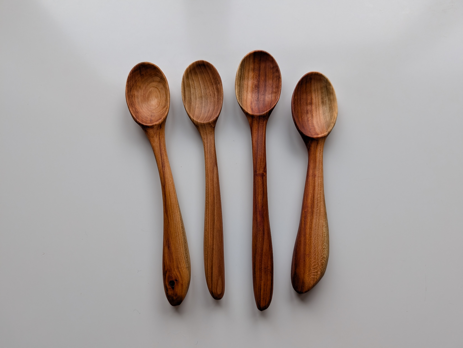 Four long-handled wooden serving spoons on a bright surface